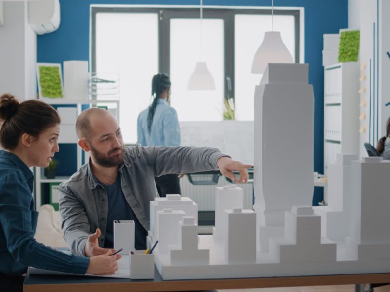 team colleagues using building model inspiration design construction layout man woman working-with maquette plan blueprints team colleagues using building model inspiration design construction layout man woman working-with maquette plan blueprints